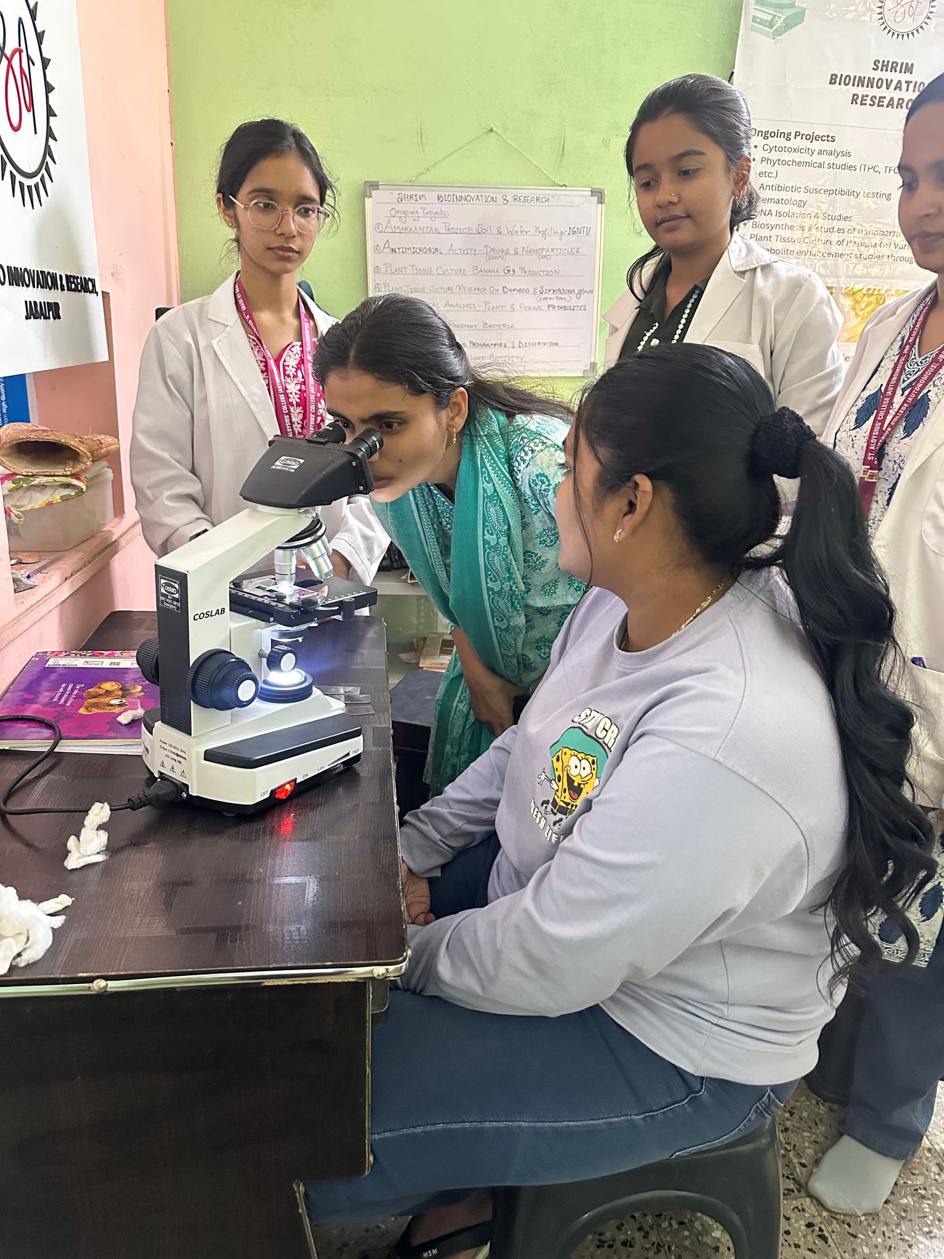 Students gathered around a microscope in a biology lab