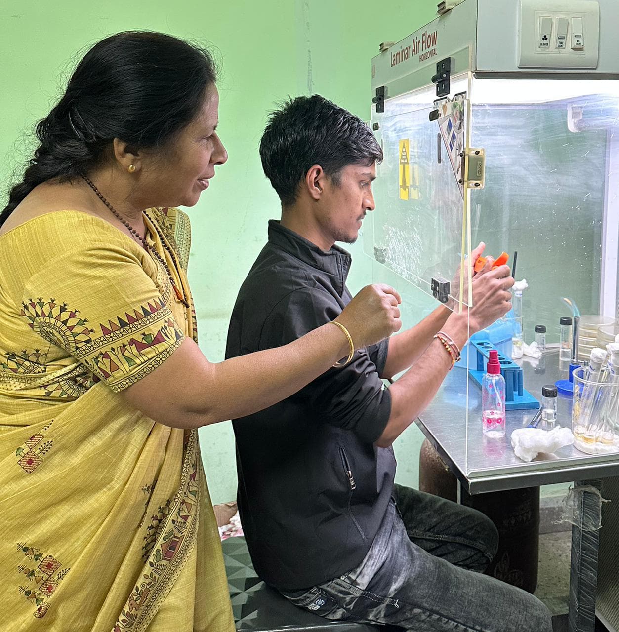Two researchers examining plant cultures in a sterile laboratory environment